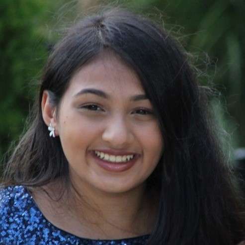 A forward facing headshot of a female team member. She has black hair, brown skin, and is smiling at the camera.